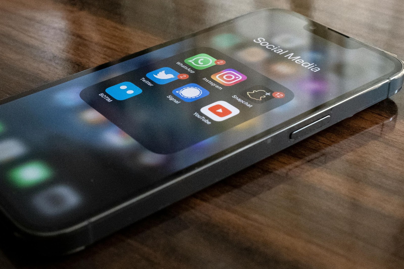 Smartphone screen showing social media folder with apps like YouTube, Instagram, and Twitter, representing video content distribution platforms.