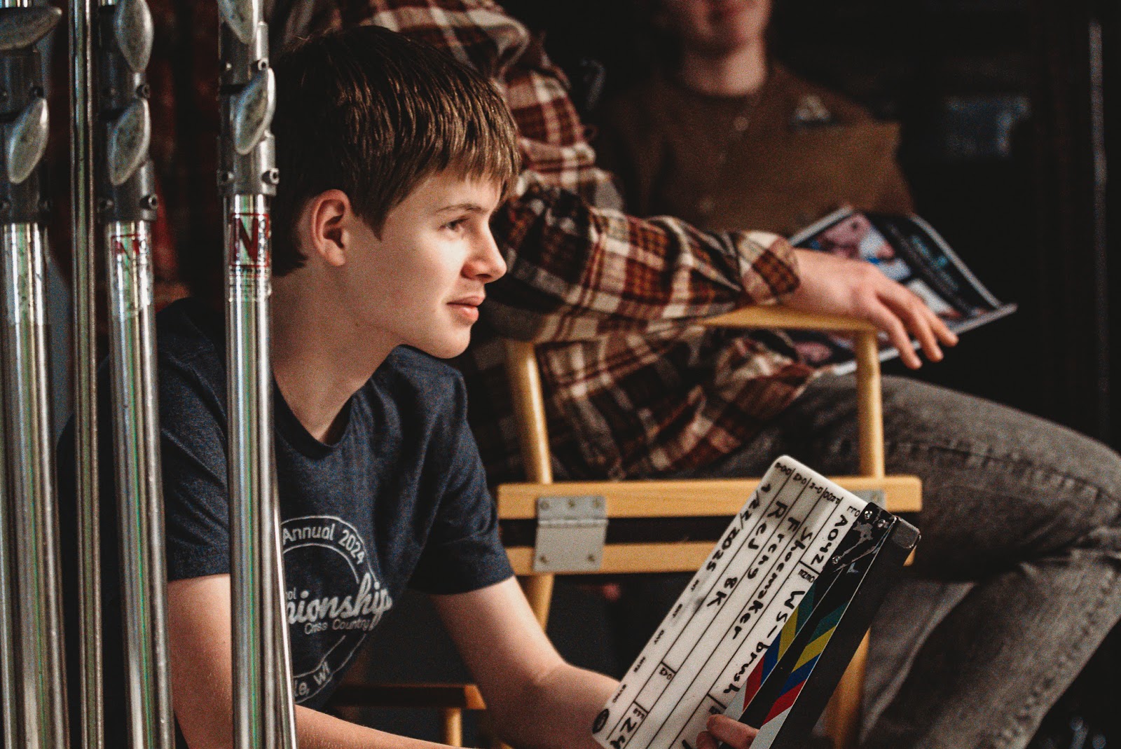 Young team member holding a film slate during a corporate video production shoot, highlighting the importance of clear communication in video marketing strategy.