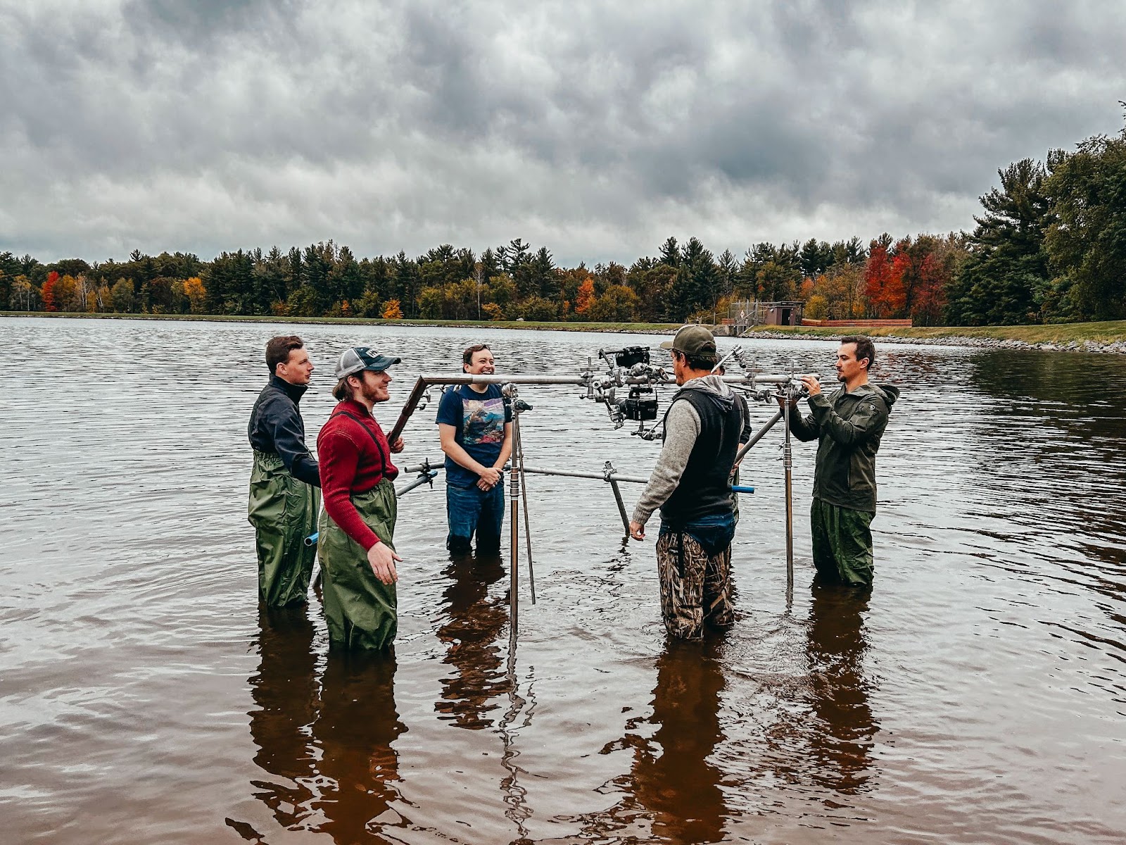 Video production crew filming in a lake using professional gear and waterproof equipment.