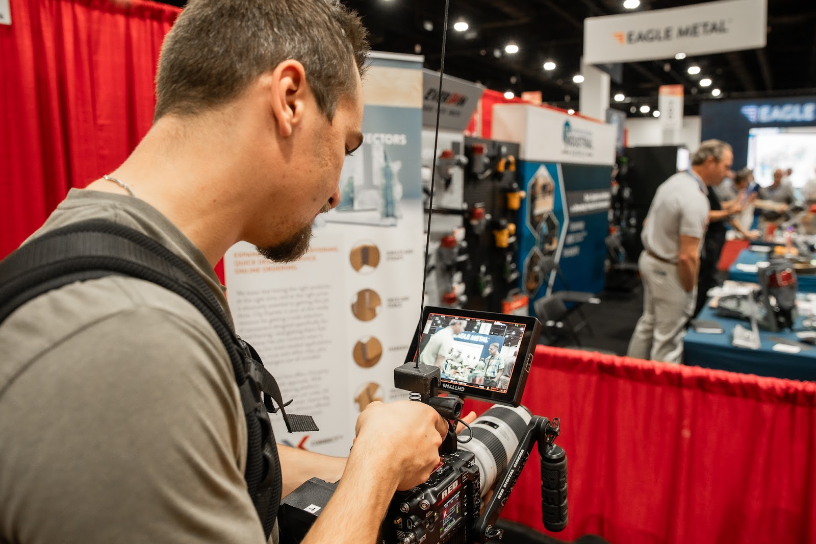 Professional videographer filming at a trade show using a RED camera, showcasing trust in video production teams and consistent brand video strategy.