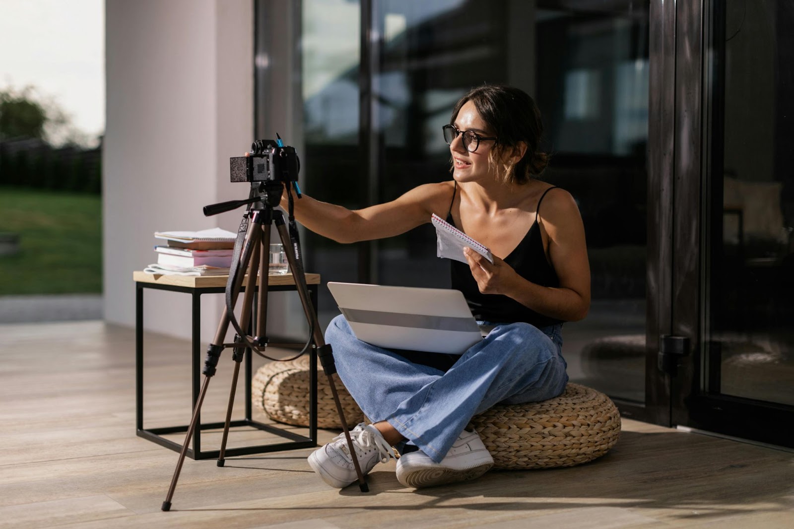 Woman creating an animated explainer video using a camera, laptop, and storyboard notes at home.
