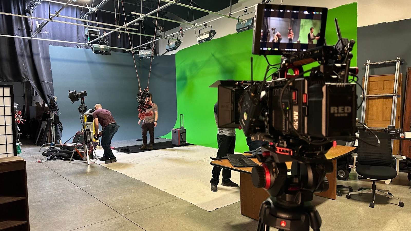 Video production team filming on a green screen set with advanced camera and harness rig.