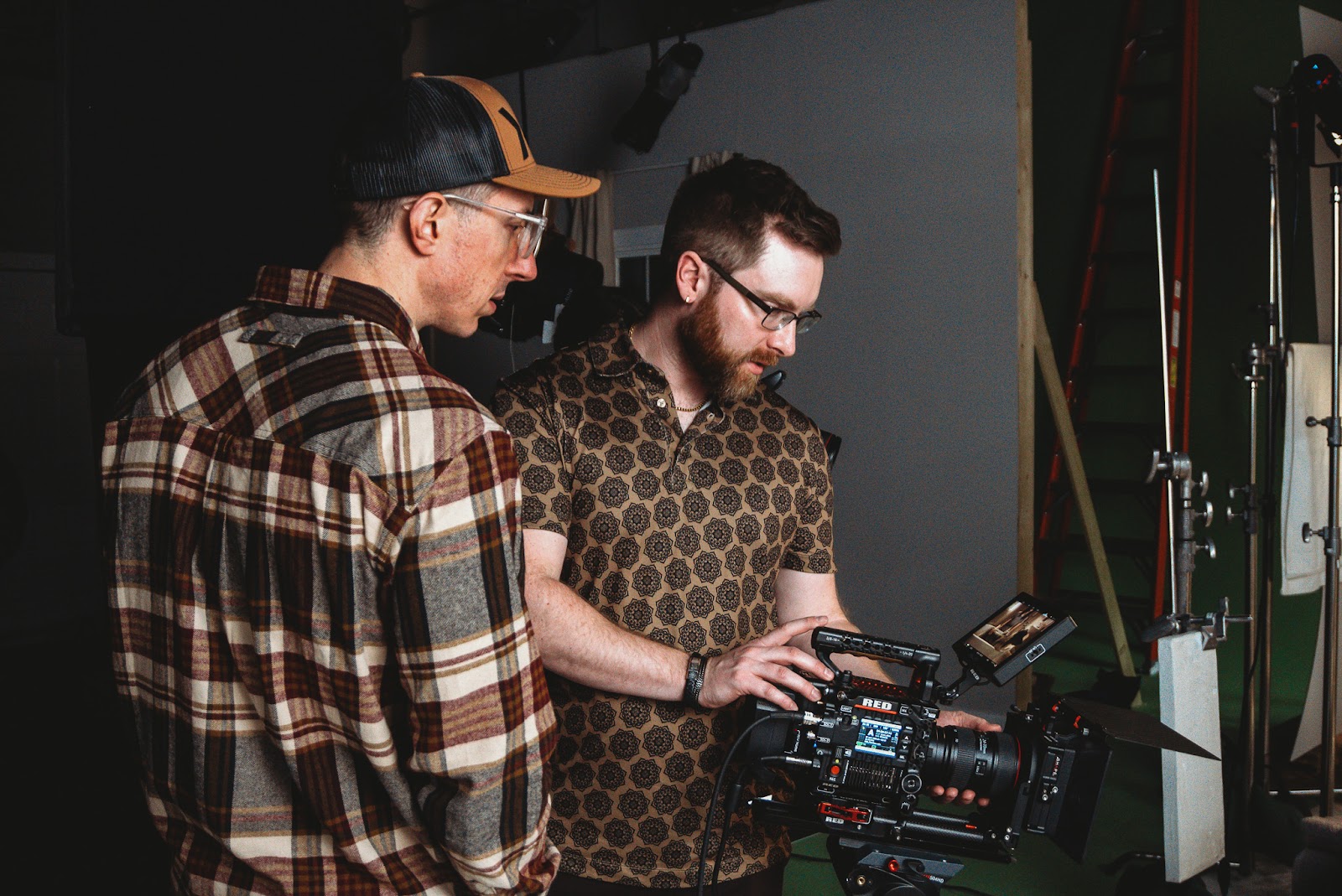 Two video production professionals reviewing footage on a RED camera, representing key team roles during a corporate video shoot.