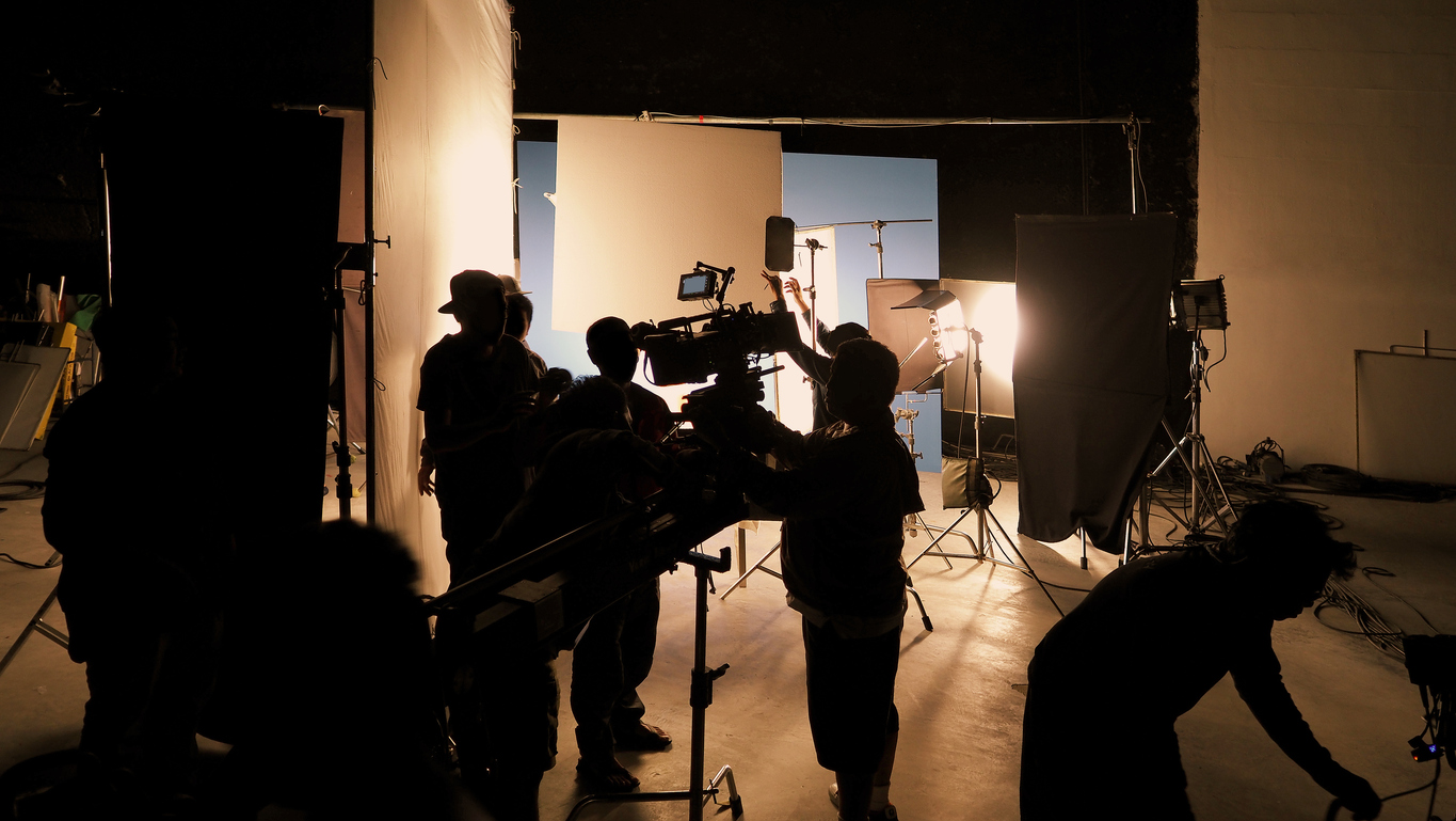 Behind-the-scenes video production crew working on set with budget-friendly equipment and lighting