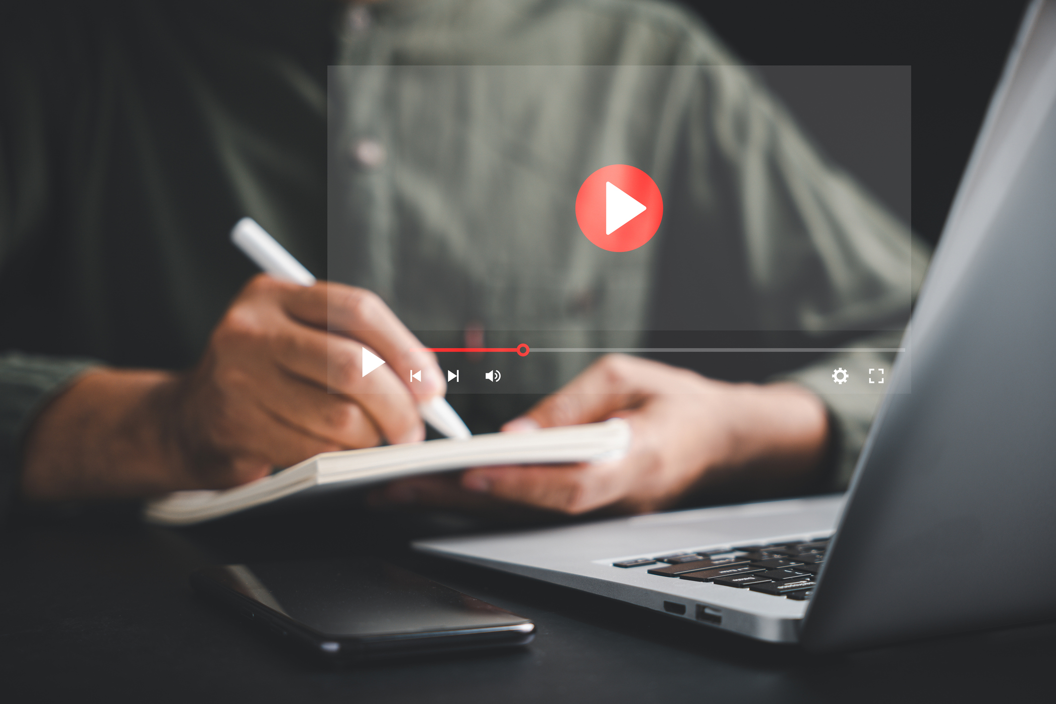 A person takes notes while reviewing video content, illustrating Backflip’s SEO strategy for optimizing video titles, descriptions, and discoverability