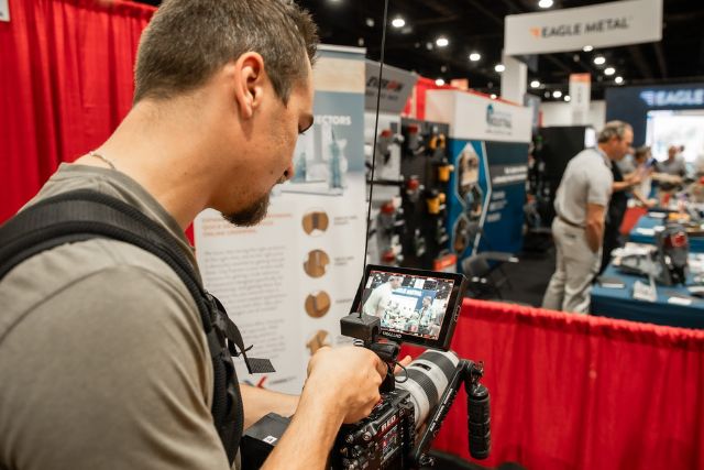 A Backflip videographer films on location at a commercial trade show using a RED cinema camera, showcasing mobile event video production services
