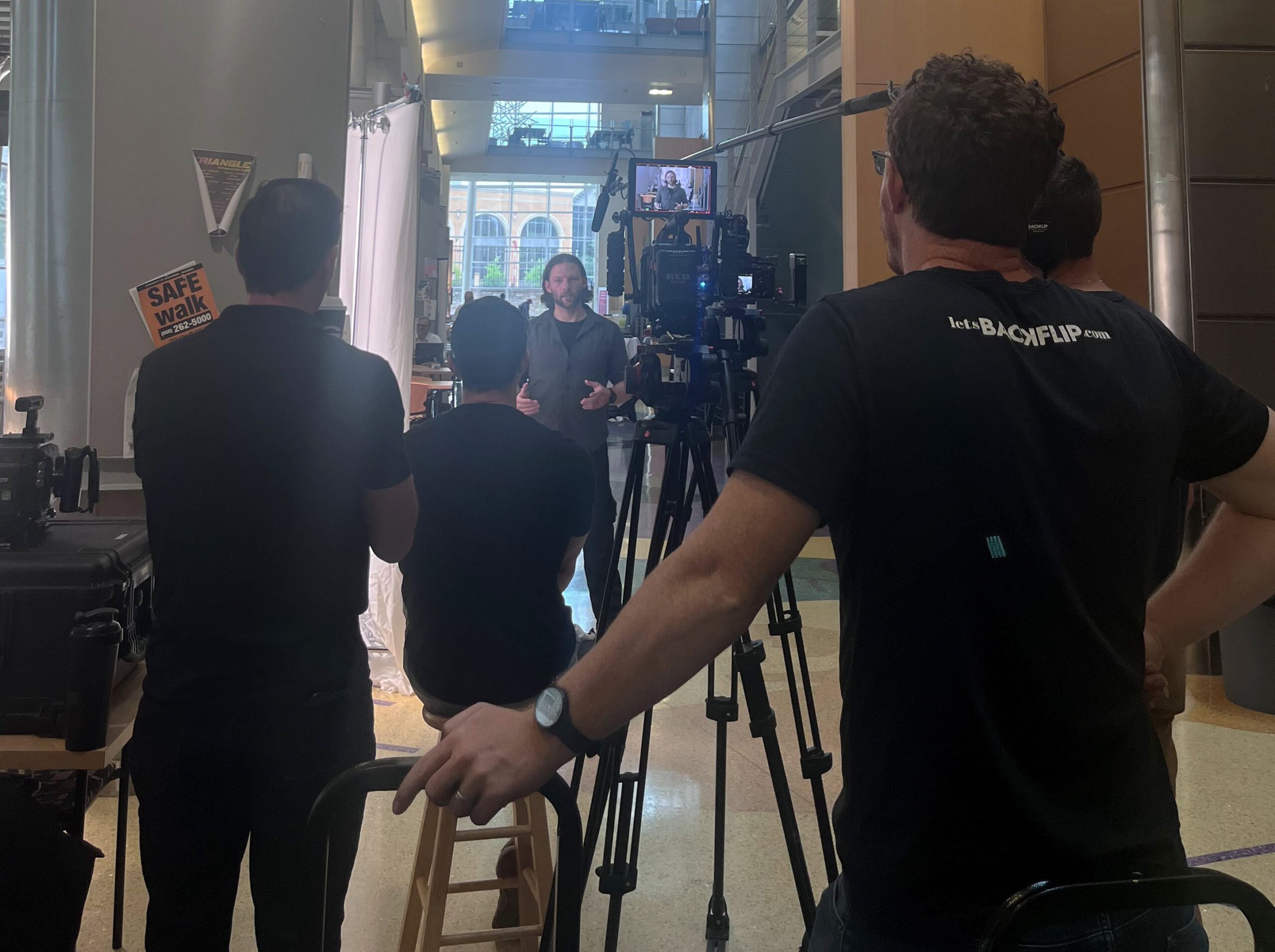The Backflip camera crew is actively filming a corporate interview, surrounded by professional lighting equipment that enhances the video production process. This setup is crucial for creating high-quality videos that effectively communicate brand messaging to the target audience.
